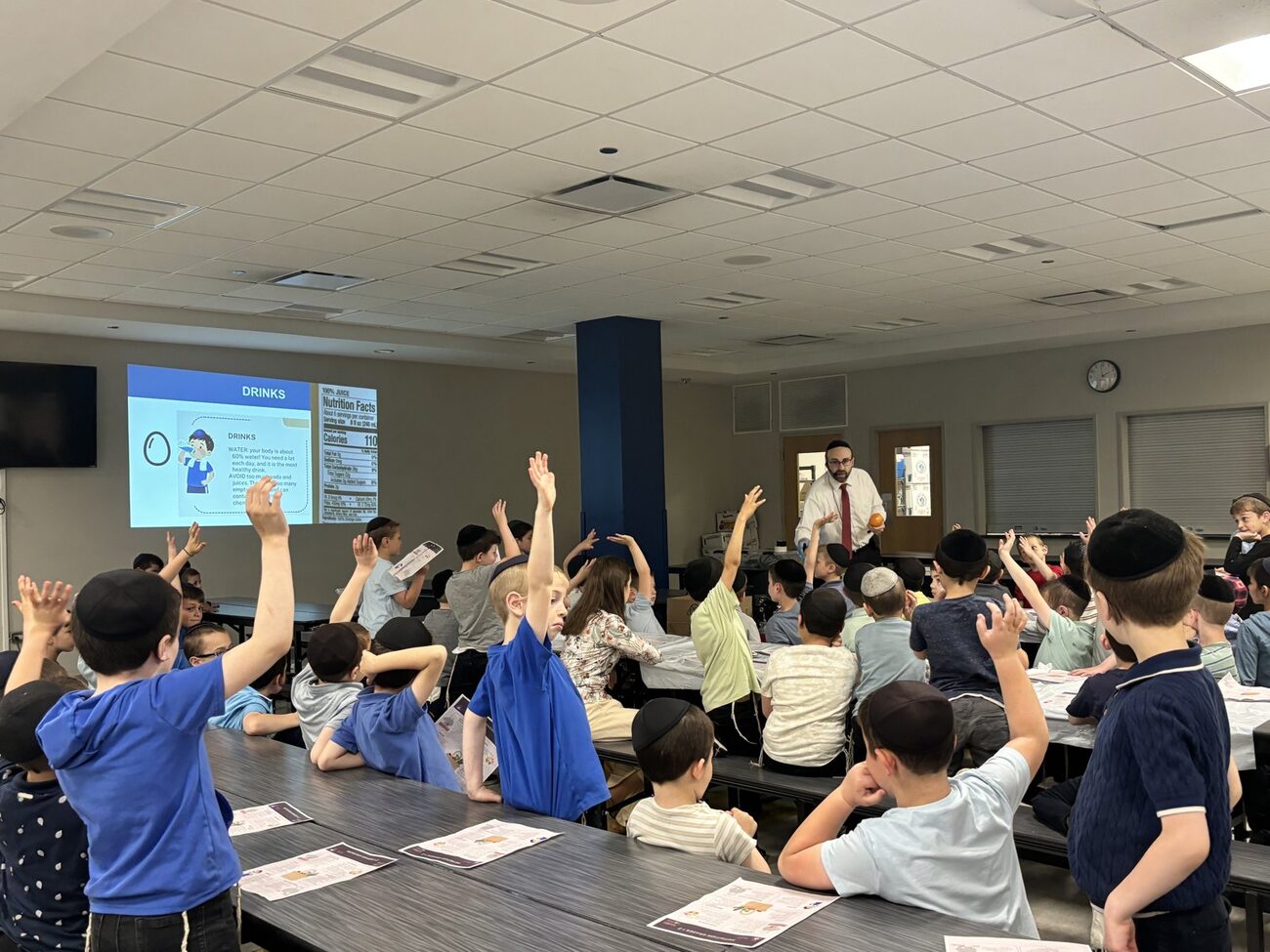 Students raising their hands at a Nourish to Flourish nutrition assembly